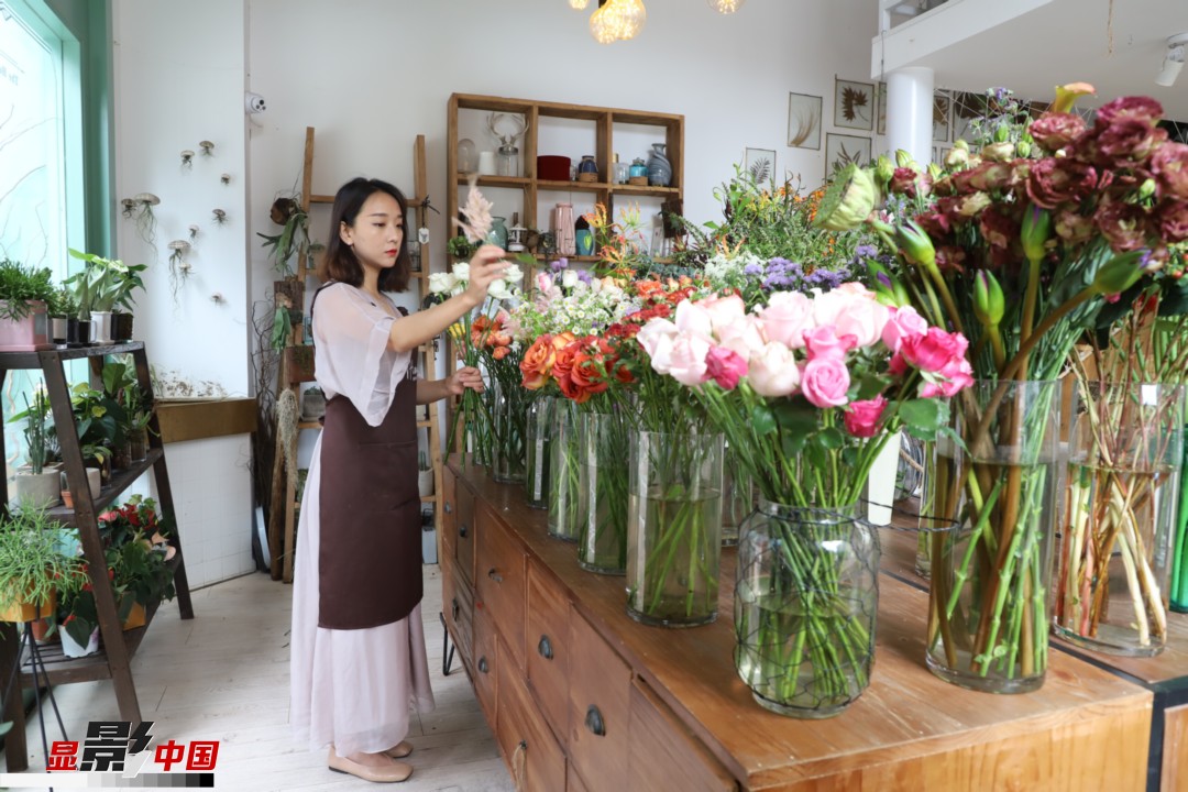 王黎媛是一名河南姑娘，在昆明念完大學(xué)后，就再也舍不下春城的藍(lán)天陽光、青山碧水，更舍不下這里的四時繁花，于是就干脆留了下來，成了一名媒體人。2017年的時候又毅然辭去工作，創(chuàng)業(yè)開起了花店，成了都市里的一名“花房姑娘”。圖為王黎媛在自己的花店中整理鮮花。新華網(wǎng) 周亞平/攝 念新洪/文